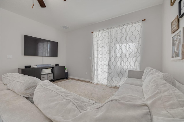 living area with light wood-style floors, ceiling fan, visible vents, and baseboards