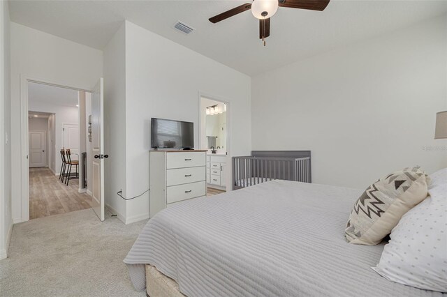 bedroom with light carpet, baseboards, visible vents, connected bathroom, and a ceiling fan