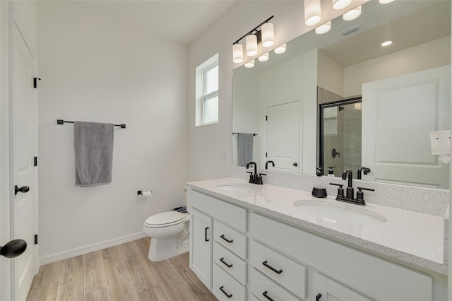 bathroom with double vanity, wood finished floors, a sink, and a shower stall