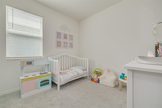 bedroom with light carpet, a crib, and baseboards