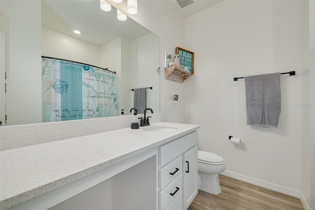 bathroom with baseboards, visible vents, toilet, wood finished floors, and vanity