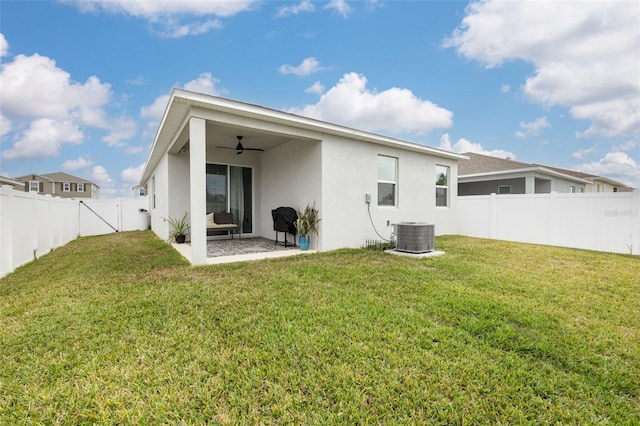 rear view of property with ceiling fan, central AC unit, a fenced backyard, a yard, and stucco siding