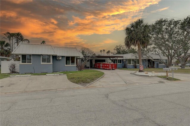 single story home with metal roof, concrete driveway, and a yard