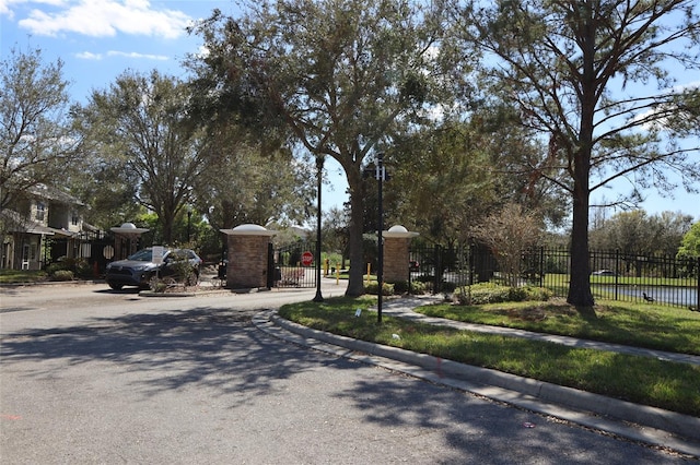 view of street featuring traffic signs, a gate, sidewalks, a gated entry, and curbs