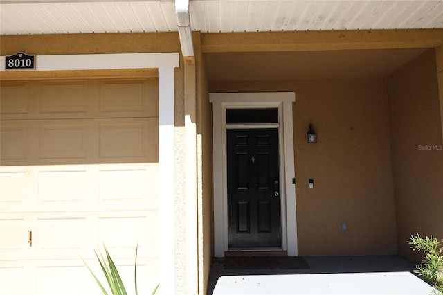 property entrance with a garage and stucco siding