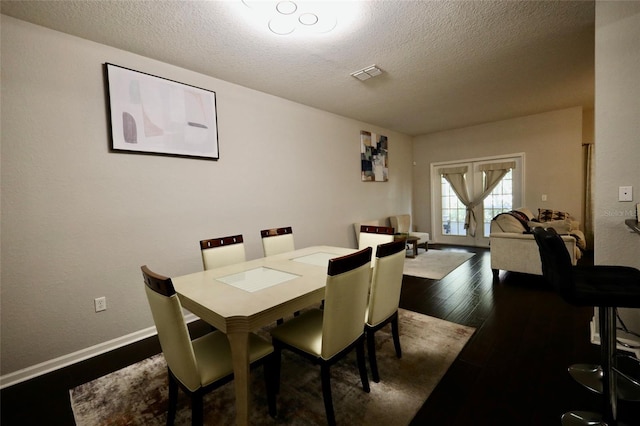 dining room featuring visible vents, dark wood finished floors, a textured ceiling, and baseboards