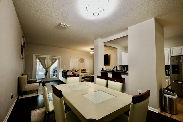 dining space featuring dark wood-style floors, a textured ceiling, and visible vents