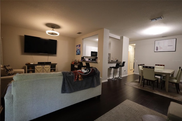 living area featuring wood-type flooring, visible vents, and a textured ceiling