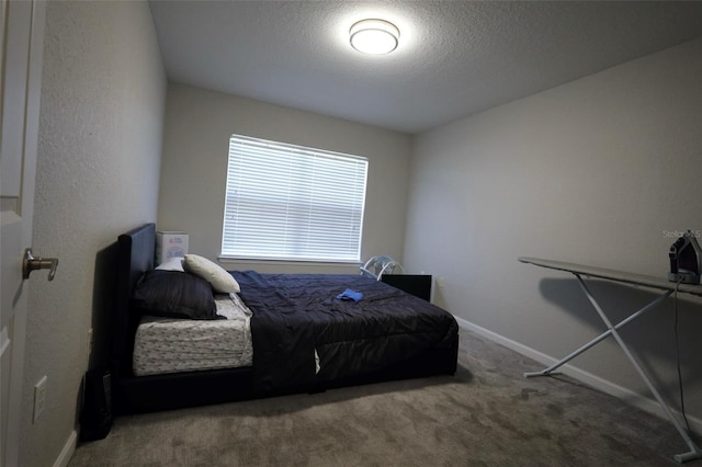 carpeted bedroom featuring a textured ceiling and baseboards