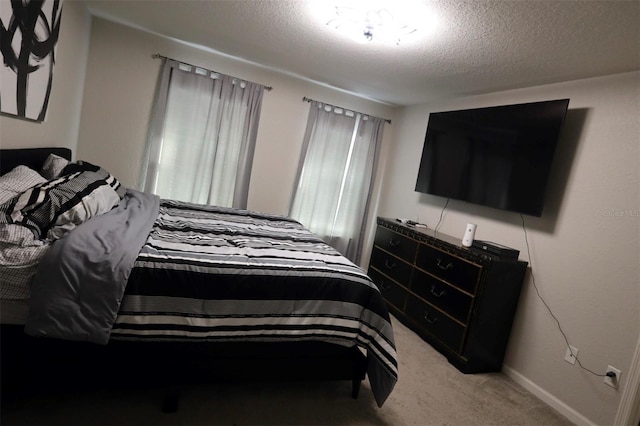 bedroom with light carpet, a textured ceiling, and baseboards