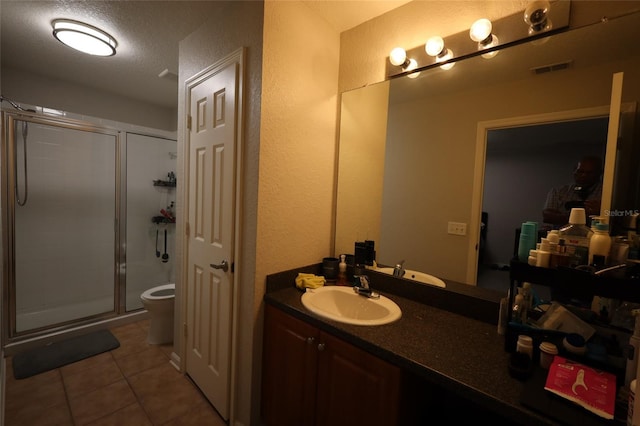 bathroom with tile patterned flooring, toilet, visible vents, vanity, and a stall shower