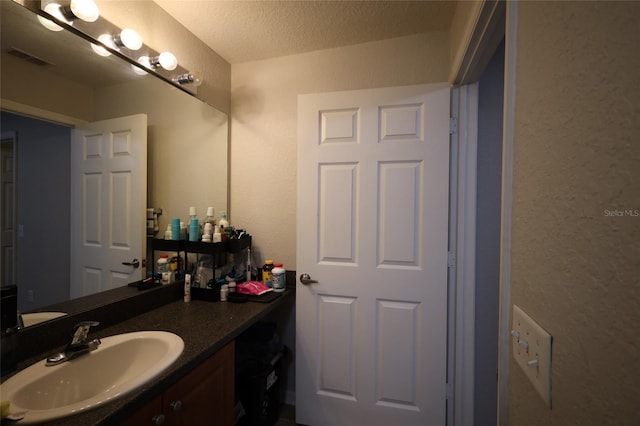 bathroom featuring visible vents, a textured ceiling, and vanity