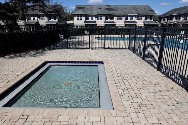 community pool featuring a patio, fence, and a residential view