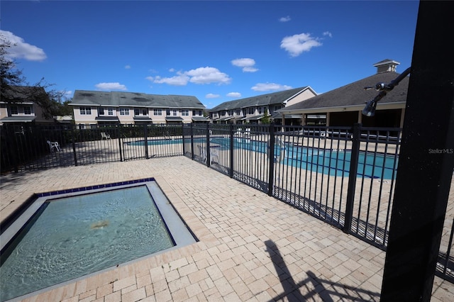 pool featuring a residential view, a patio area, and fence