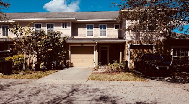 multi unit property featuring a garage and concrete driveway