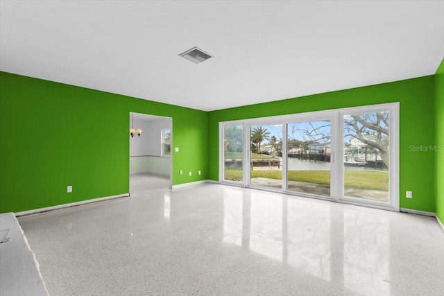 unfurnished living room with baseboards, an accent wall, visible vents, and speckled floor