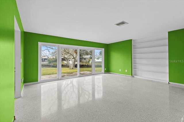 empty room featuring visible vents, baseboards, and speckled floor