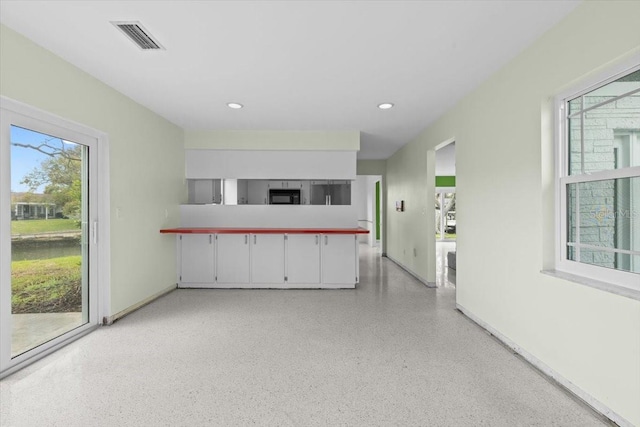 interior space featuring light speckled floor, baseboards, visible vents, and recessed lighting