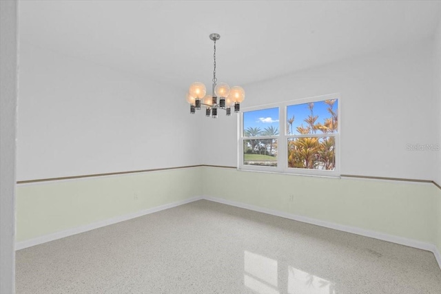 unfurnished room featuring a chandelier, speckled floor, and baseboards