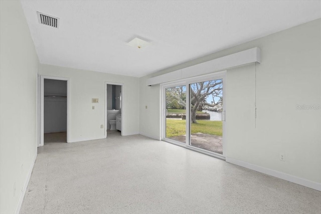 unfurnished bedroom with baseboards, speckled floor, visible vents, and access to exterior