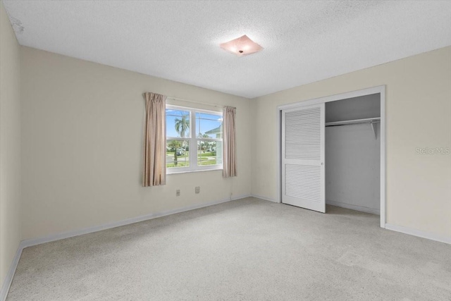 unfurnished bedroom featuring a textured ceiling, a closet, light carpet, and baseboards