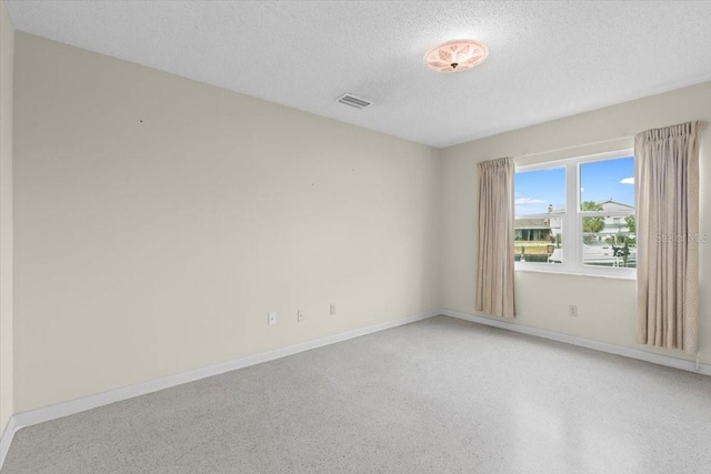 unfurnished room with visible vents, baseboards, light speckled floor, and a textured ceiling