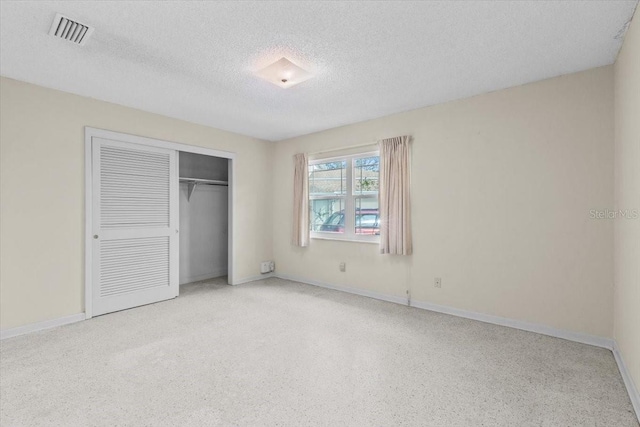 unfurnished bedroom featuring a closet, visible vents, a textured ceiling, and baseboards