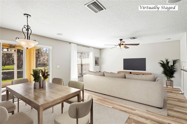 dining room with a textured ceiling, a ceiling fan, visible vents, and light wood-style floors