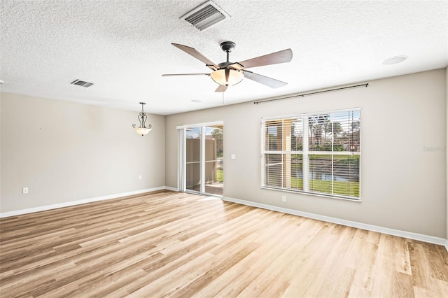 unfurnished room featuring plenty of natural light, light wood-style flooring, visible vents, and baseboards