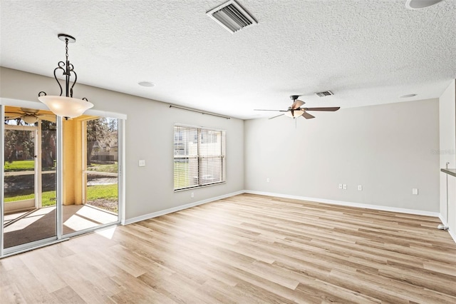 unfurnished living room featuring a textured ceiling, visible vents, and light wood-style floors