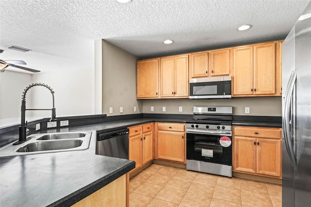 kitchen featuring light tile patterned floors, visible vents, dark countertops, appliances with stainless steel finishes, and a sink