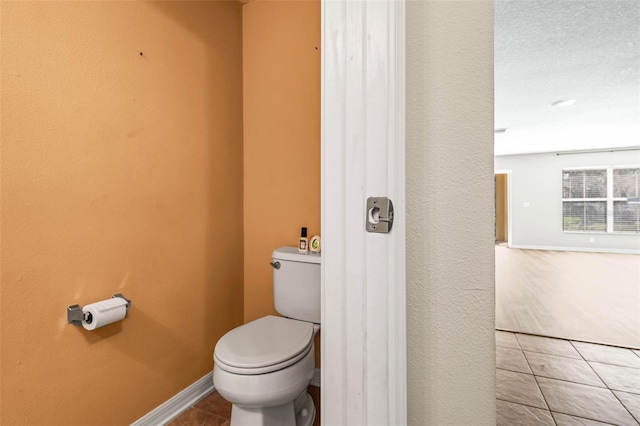 bathroom with tile patterned flooring, baseboards, and toilet