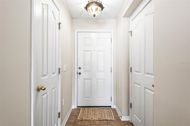 entryway featuring dark tile patterned flooring and baseboards