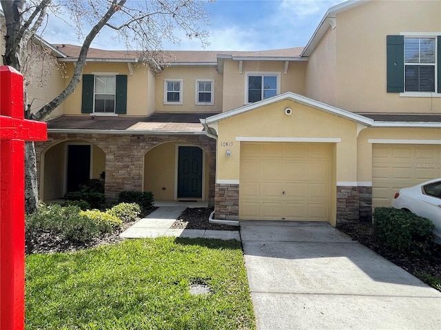 multi unit property featuring driveway, stone siding, and stucco siding