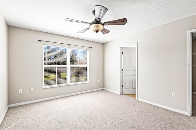 carpeted spare room featuring ceiling fan, a textured ceiling, and baseboards