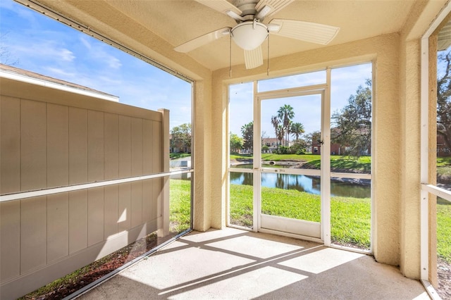 unfurnished sunroom with a water view and ceiling fan