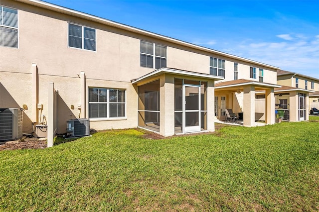 back of house with central air condition unit, a patio area, a lawn, and stucco siding