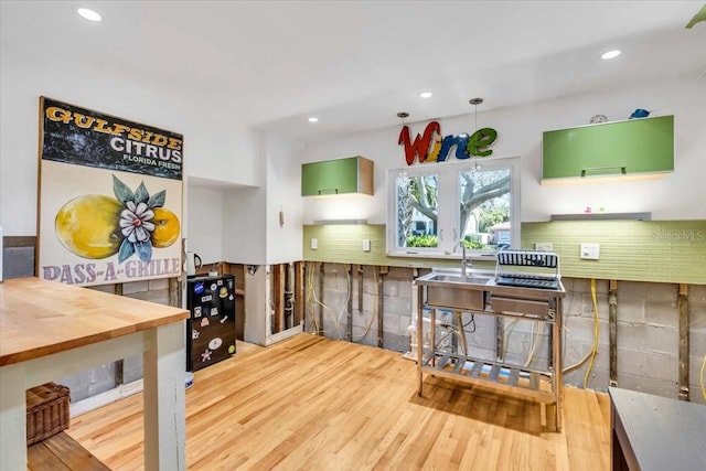 kitchen featuring a sink, tasteful backsplash, wood finished floors, and recessed lighting