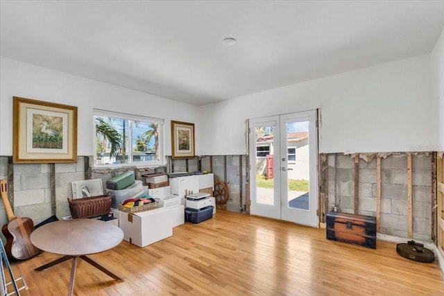 living area with light wood finished floors, french doors, and a healthy amount of sunlight