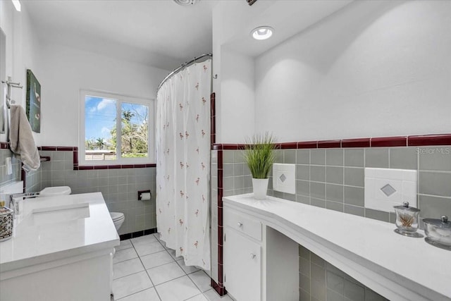 full bathroom featuring toilet, a wainscoted wall, tile patterned flooring, vanity, and tile walls