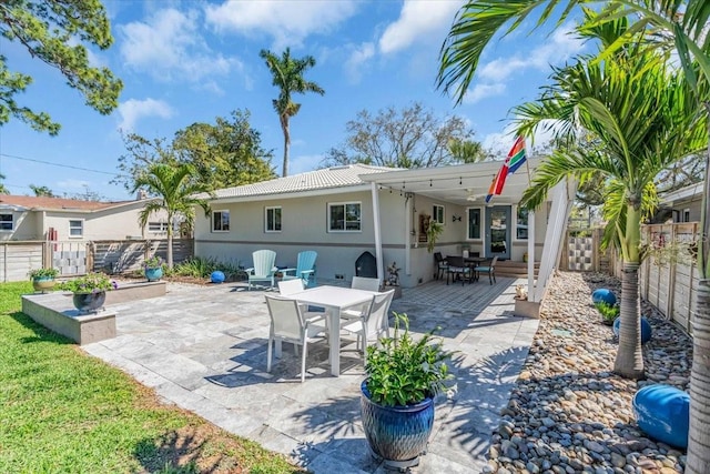 back of house featuring stucco siding, a fenced backyard, a patio area, and outdoor dining space