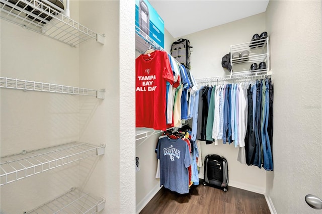 walk in closet with dark wood-style flooring