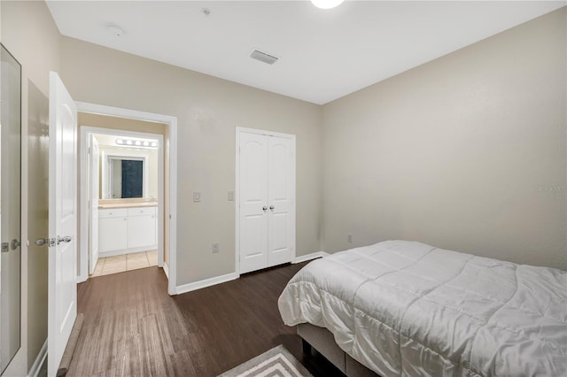 bedroom with dark wood-type flooring, a closet, visible vents, and baseboards