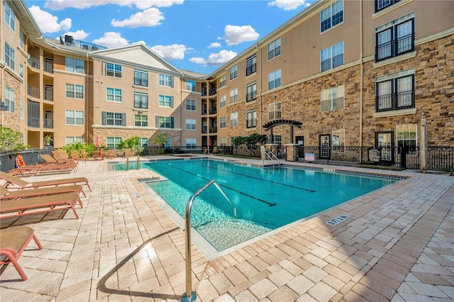 community pool with a patio area and fence