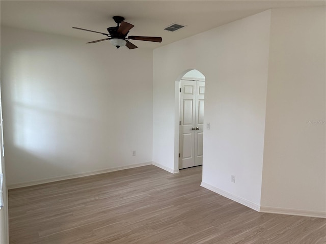 spare room with light wood finished floors, visible vents, arched walkways, and baseboards