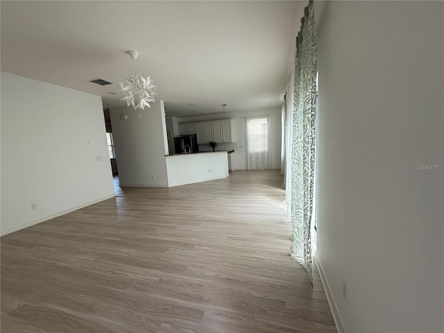 unfurnished living room with light wood-style flooring, visible vents, and baseboards