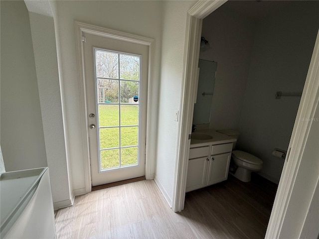 doorway featuring light wood finished floors, baseboards, and a sink