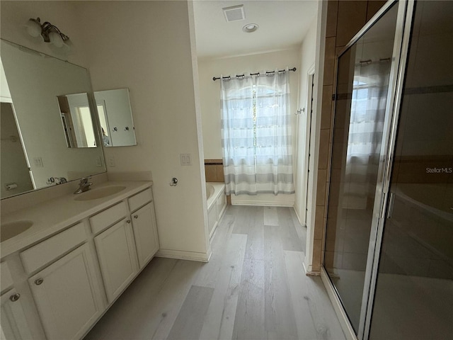 bathroom with a stall shower, visible vents, a sink, and wood finished floors