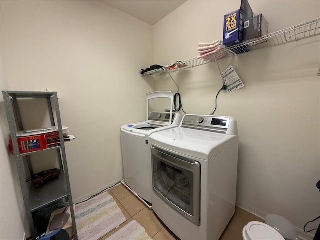 washroom featuring light tile patterned floors, laundry area, washing machine and dryer, and baseboards