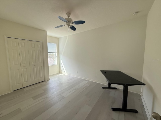 unfurnished bedroom featuring ceiling fan, a closet, baseboards, and wood finished floors